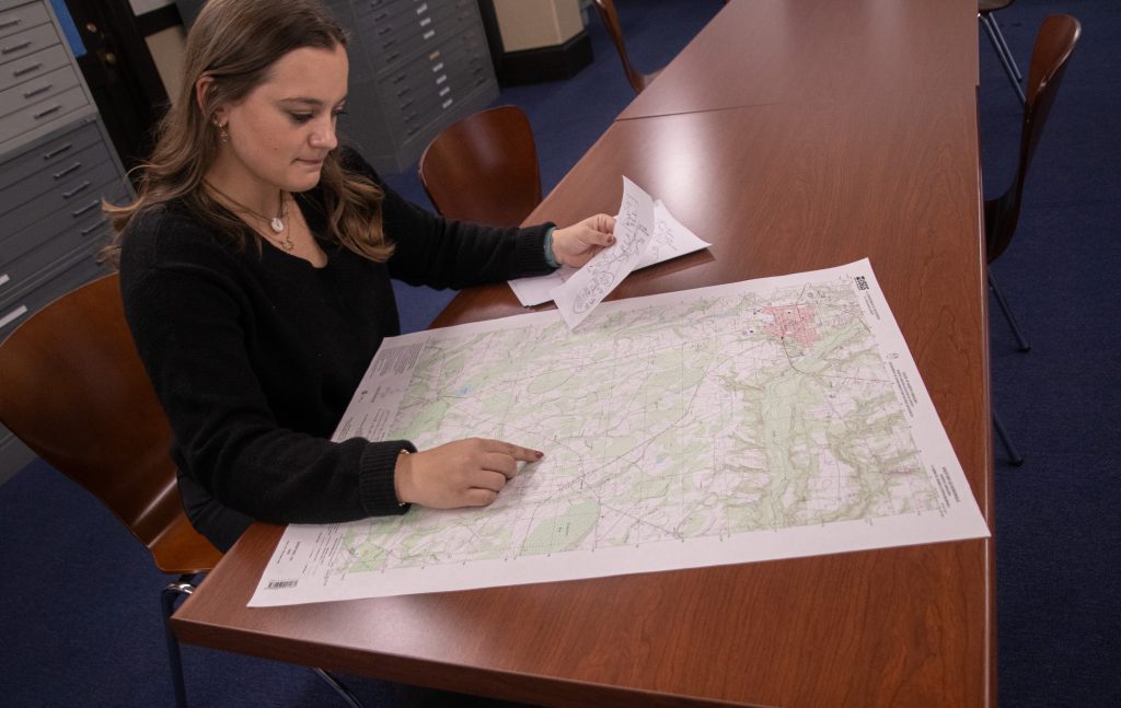 Hailey Richardson looks down at a drafting table with a map on it.