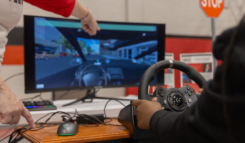 A student practices driving on a driving simulator.