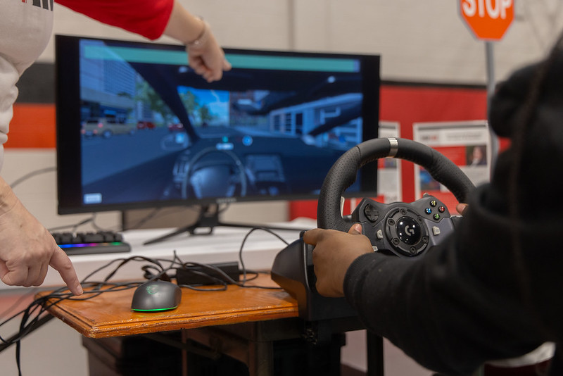 A student practices driving on a driving simulator.