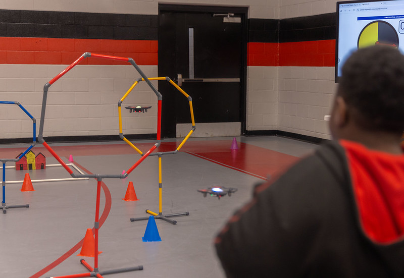 A student flies a small drone through an obstacle course.